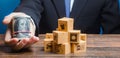 Businessman holds out a bundle of dollars near a pile of boxes. Profit, Superprofits. Investments financing in production, taxes Royalty Free Stock Photo