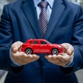 Businessman holds red toy car, illustrating car purchase concepts Royalty Free Stock Photo