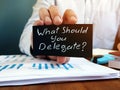 Businessman holds sign What Should You Delegate. Delegation concept Royalty Free Stock Photo