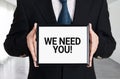 Businessman holds a signboard with the message we need you. Human resources recruitment or employment