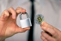 A businessman holds a silver padlock and physical version of bitcoin in his hands. Prohibition of cryptocurrencies, regulations,