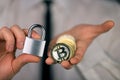 A businessman holds a silver padlock and physical version of bitcoin in his hands. Prohibition of cryptocurrencies, regulations,