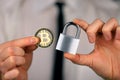 A businessman holds a silver padlock and physical version of bitcoin in his hands. Prohibition of cryptocurrencies, regulations,