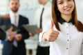 Businessman holds thumbs up in background are business partners