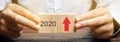 Businessman holds wooden blocks with the inscription 2020 and an up arrow. The forecast concept for 2020. Business forecasting.