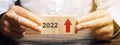 Businessman holds wooden blocks with the inscription 2022 and an up arrow. The forecast concept for 2022. Business forecasting.