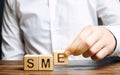 Businessman holds wooden blocks with the word SME. Small and medium-sized enterprises - commercial enterprises that do not exceed Royalty Free Stock Photo