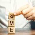 Businessman holds wooden blocks with the word SME. Small and medium-sized enterprises - commercial enterprises that do not exceed