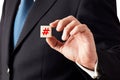 Businessman holds a wooden cube with a hashtag icon Royalty Free Stock Photo