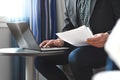 Businessman in hotel room reading business report paper.