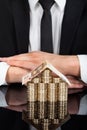 Businessman with house made of currency at desk Royalty Free Stock Photo