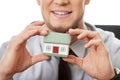 Businessman with house model by a desk.