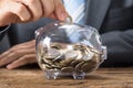 Businessman Inserting Coin In Transparent Piggy Bank