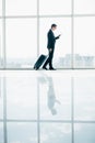 Businessman at international airport moving to terminal gate for airplane travel trip looking in phone in hand Royalty Free Stock Photo