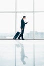 Businessman at international airport moving to terminal gate for airplane travel trip looking in phone in hand Royalty Free Stock Photo