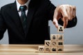 businessman investor hand arranging wood block with business finance icon on desk