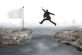 Businessman jump on cliff with white flag and cloudy cityscape