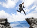 Businessman jumping over danger precipice