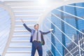 Businessman keeping arms raised and expressing positive while standing outdoors with office building in the background