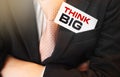 Businessman keeps a card with text Think Big in upper suit pocket. Business motivational concept