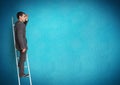 Businessman on ladder looking at a distance