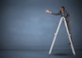 Businessman on ladder stretching his hand to reach