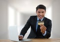 Businessman with laptop at desk with bank card with bright background