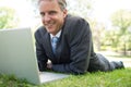 Businessman with laptop lying in park Royalty Free Stock Photo