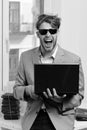 Businessman with laptop and pile of books on office window background. Cool guy sits on table and works. Working online Royalty Free Stock Photo