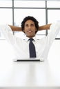 Businessman With Laptop Sitting At Desk In Office Thinking