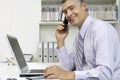 Businessman With Laptop Using Cellphone At Desk Royalty Free Stock Photo