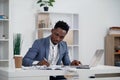 Businessman with laptop. Young African businessman is typing something on laptop in his office. Royalty Free Stock Photo