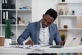 Businessman with laptop. Young African businessman is typing something on laptop in his office. Royalty Free Stock Photo
