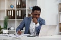 Businessman with laptop. Young African businessman is typing something on laptop in his office. Royalty Free Stock Photo