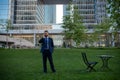 Businessman on large grass field near modern office building. Business man talking on phone in park of megapolice. Royalty Free Stock Photo