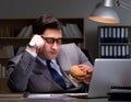 Businessman late at night eating a burger