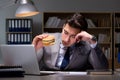 The businessman late at night eating a burger