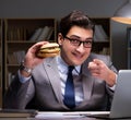 Businessman late at night eating a burger