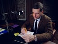 Businessman late at night works with papers while sitting at the table.