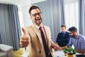 Businessman leader looking at camera in modern office with businesspeople working at the background. Royalty Free Stock Photo