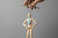 Businessman leader in tie on gray background. Deryannaya doll on the threads that pulls the puppeteer. Concept of how to manage