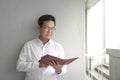 Businessman leaning against white wall, reading at his appointment book