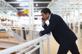 Businessman leaning on railing and talking on mobile phone in a modern office Royalty Free Stock Photo