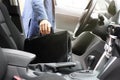 Businessman with leather briefcase sits on driver seat in car with modern interior Royalty Free Stock Photo