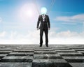 Businessman of light bulb head landing on chessboard ground