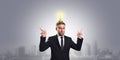 Businessman with a light bulb over his head and points his hands up on a gray background with a copy space. Business concept idea Royalty Free Stock Photo