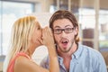 Businessman listening to rumor which female colleague is whispering Royalty Free Stock Photo