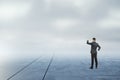 Businessman looking into the distance on abstract dull sky and ground background