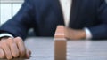 Businessman looking at domino bars, chain reaction outcome if one bar falls down