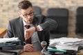 Businessman looking at his wristwatch at table in office. Time management concept Royalty Free Stock Photo